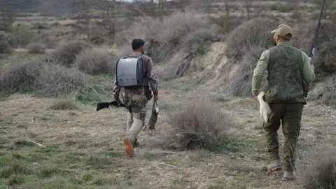 Two unrecognizable hunters walking with a rabbit and a ferret Stock Footage 270245103