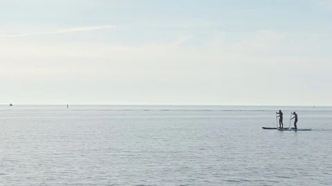 Two unrecognizable men are swimming in the sea on paddleboards or on supboards Video stock 103854981