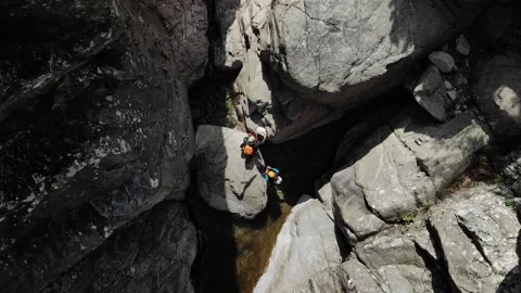 Two unrecognizable people canyoning. Three canyoneers moving foward to abseil Stock Footage 201524989