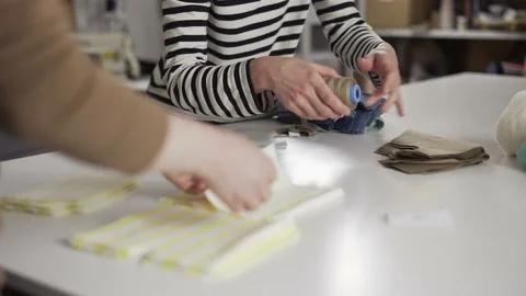 Two unrecognizable seamstresses working with patterns and fabrics on the table Stock Footage 157158667