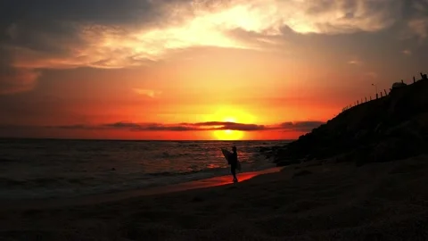 Two unrecognizable surfers coming out of the sea with a beautiful view of the Stock Footage 195130991