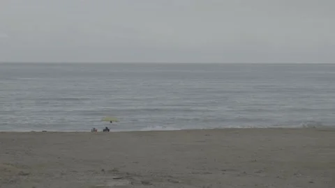 Two unrecognizable tourists on a beach under an umbrella Stock Footage 185431728