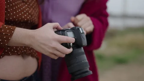 Two unrecognizable women analyse some pictures on camera Stock Footage 280212571