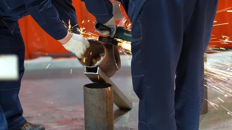 Two unrecognizable workers wear protective gloves, grind edges of metal pipe Stock Footage 126357472