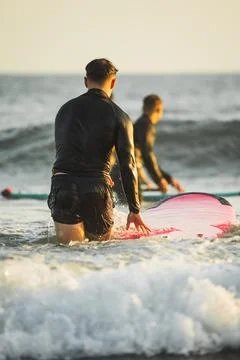 Two unrecognizable young men at the beach with their surfboards Stock Photos