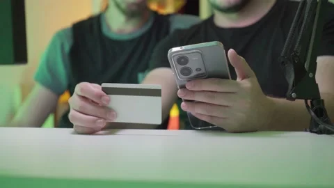 Two unrecognizable young men thinking about making a purchase via cell phon.. Stock Footage 238862239