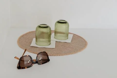 Two upside down green ribbed glass cups placed on white napkins over a round mat Stock Photos