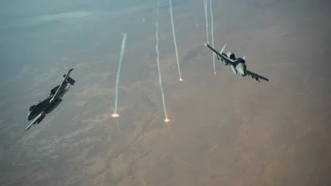 Two U.S. Air Force A-10 Thunderbolts releasing flares and peel away over desert Stock Footage 297664479