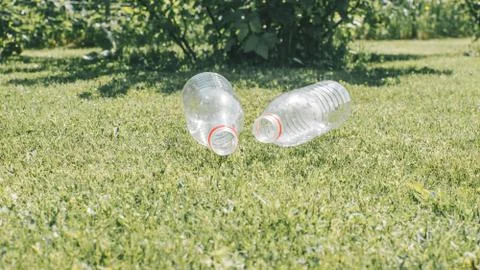 Two used plastic bottles on the grass background. Waste separation concept. Stock Photos