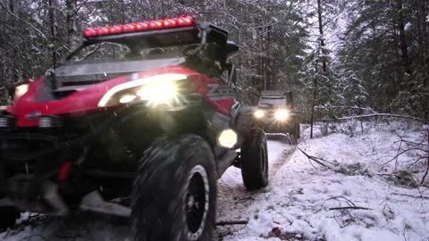 Two utv sxs off-road vehicles with the headlights on in the evening snow forest Stock Footage 188560347