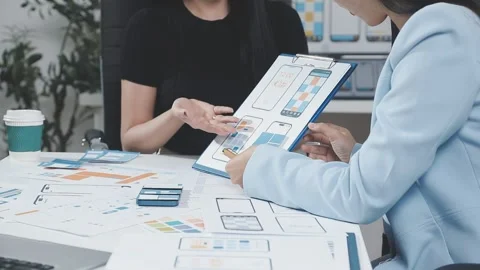 Two UX UI designers brainstorming mobile app wireframes in a modern startup.. Stock Footage 321352979