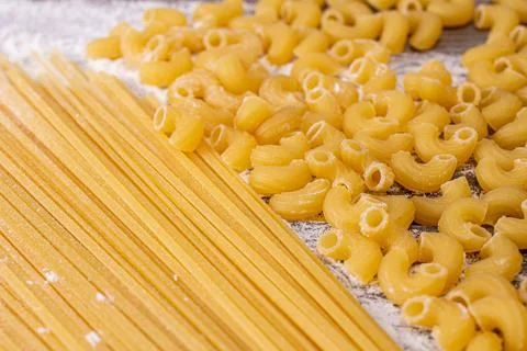 Two varieties of pasta with the texture of spaghetti flour on a wooden table Stock Photos