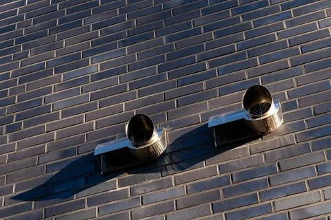Two ventilation pipes installed on a brick wall in an urban setting Stock Photos