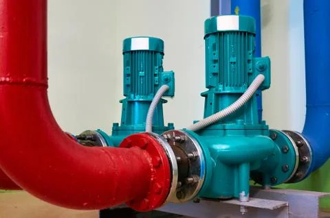 Two vertical engine painted blue with pumps connected to pipes painted red a Stock Photos