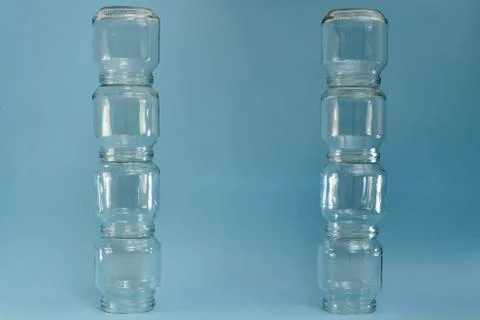 Two vertical parallel rows of glass jars on a blue background. Stock Photos