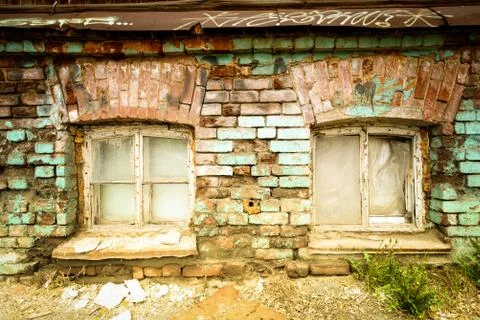 Two very old aged windows set in a derelict building with peeling paint and c Stock Photos