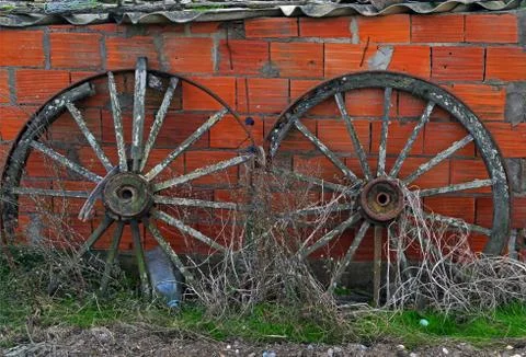 Two very old wheels attached to the brick wall Stock Photos