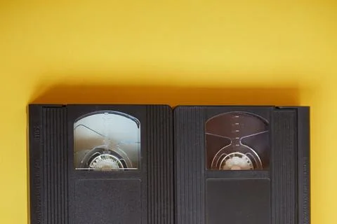 Two VHS format videotapes on a yellow background, videotape at the beginning  Stock Photos