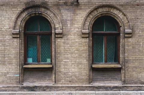 Two vintage arched windows in a wall of yellow bricks. Green - the colors of sea Stock Photos