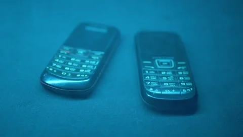 Two Vintage Mobile Phones Lying In Blue Fog And Smoke With Cyber Light Vídeos de archivo 330112169