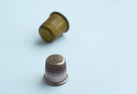 Two vintage thimbles stand in a row isolated on a colored background. Stock Photos