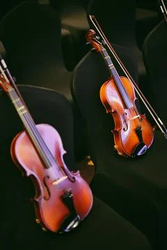 Two violins on some chairs Stock Photos