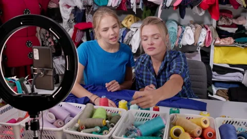 Two vloggers choose the right color of thread for purple fabric. Video stock 244862582