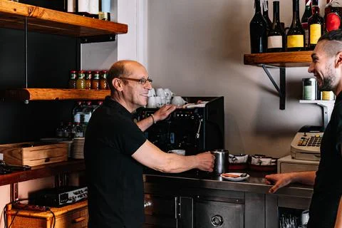 Two waiters working together while talking. Waiter giving an order to his co Stock Photos