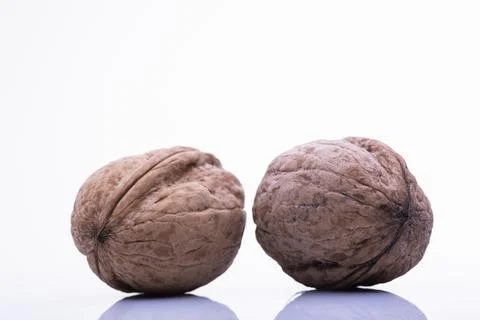 Two walnuts rest on a white surface Foto stock