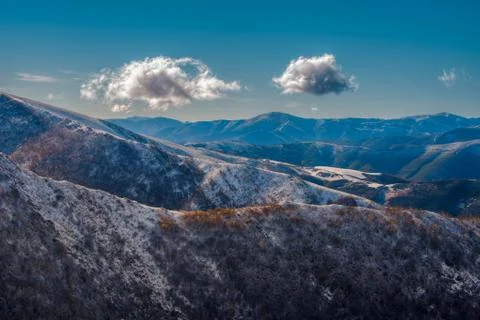 Two wandering clouds float over the snowy mountains Stock Photos