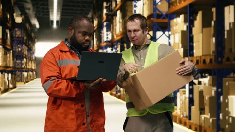 Two warehouse colleagues organizing pallets and packages with laptop Stock Footage 332909500