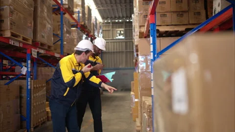 Two warehouse workers are reviewing the list of items based Stock Footage 308935927