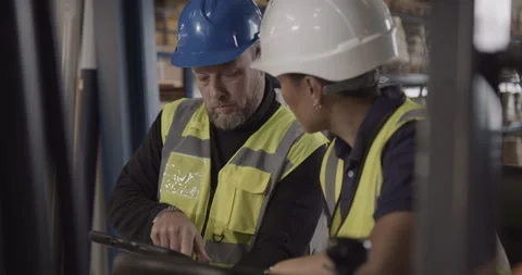 Two Warehouse Workers Looking at Digital tablet Discussing Supply chain Video stock 255562997