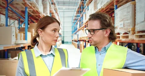 Two warehouse workers, man and woman in yellow uniform, collect parcels for Stock Footage 151784449