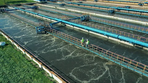 Two wastewater operators walking along the pipes at a sewage cleaning facility Stock-Footage 145257438