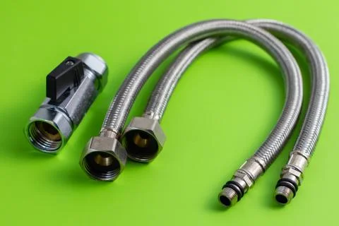 Two water hoses in metal braid and ball valve  on green Stock Photos