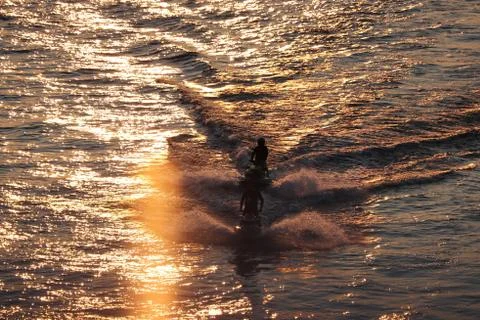Two watercraft float on the water at sunset Stock Photos