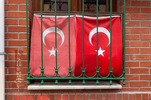 Two waving Turkish Flag in window with grate, brick wall Stock Photos