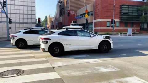Two Waymo self-driving cars driving through an intersection, 4K Stock Footage 294440302