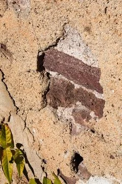 Two weathered bricks showing through hole in old concrete wall of a building. Stock Photos