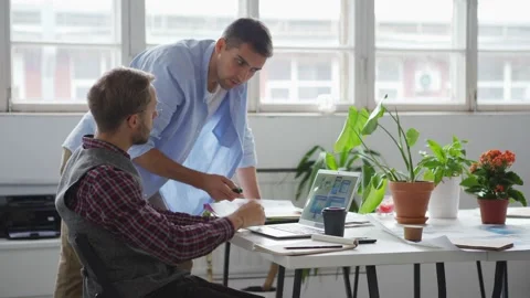 Two web designers discussing interface samples at desk 스톡 동영상 142509423