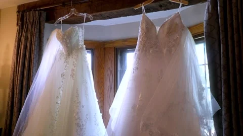 Two wedding dresses hanging in a window Stockbeeldmateriaal 320468035