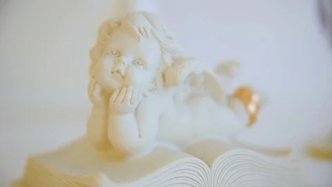 Two wedding gold rings. angel figure statuette. angel on book. closeup Stock Footage 83008201