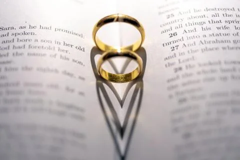 Two wedding Ring on the bible with shadow of heart shape on the page Stock Photos