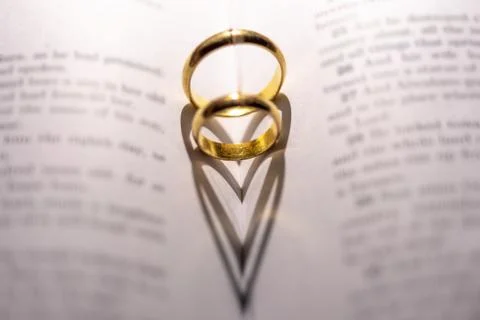 Two wedding Ring on the bible with shadow of heart shape on the page Stock Photos