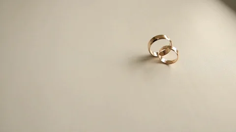 Two wedding ring rolling on the white surface Stock Footage 86987132