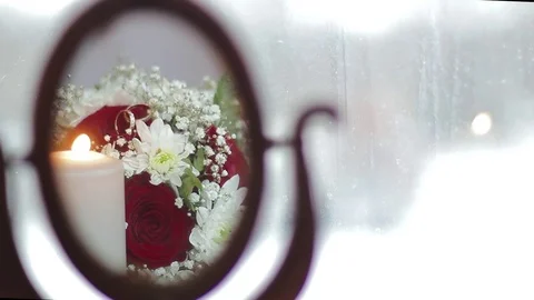 Two wedding rings are lying next to a burning candle. We see it in the mirror. Stock Footage 77588505