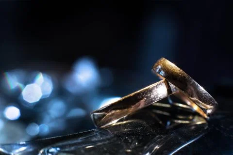 Two wedding rings of different sizes made in gold on blue bokeh background Foto stock