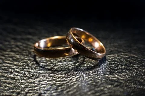 Two wedding rings of different sizes made in gold on the black leather Stock Photos
