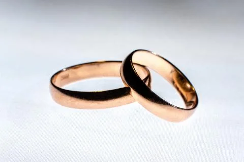 Two wedding rings of different sizes made in gold on the white light surface Foto stock